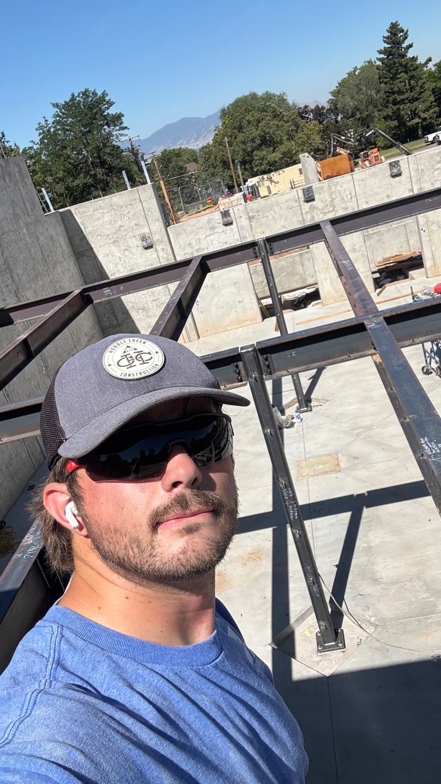 Dylan on a structural steel job site with steel beams and concrete walls behind him
