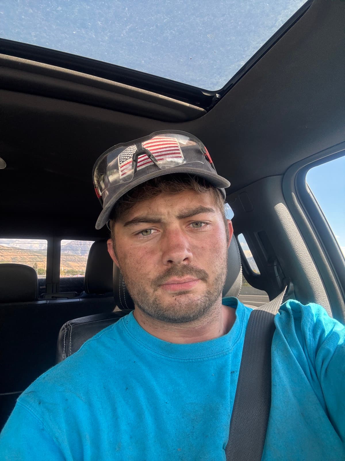 Selfie of Dylan in his truck, safety glasses resting on his cap
