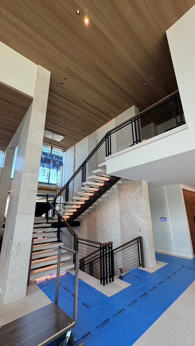 Open staircase with floating treads and black horizontal-bar steel railing, with cable railing on the landing above