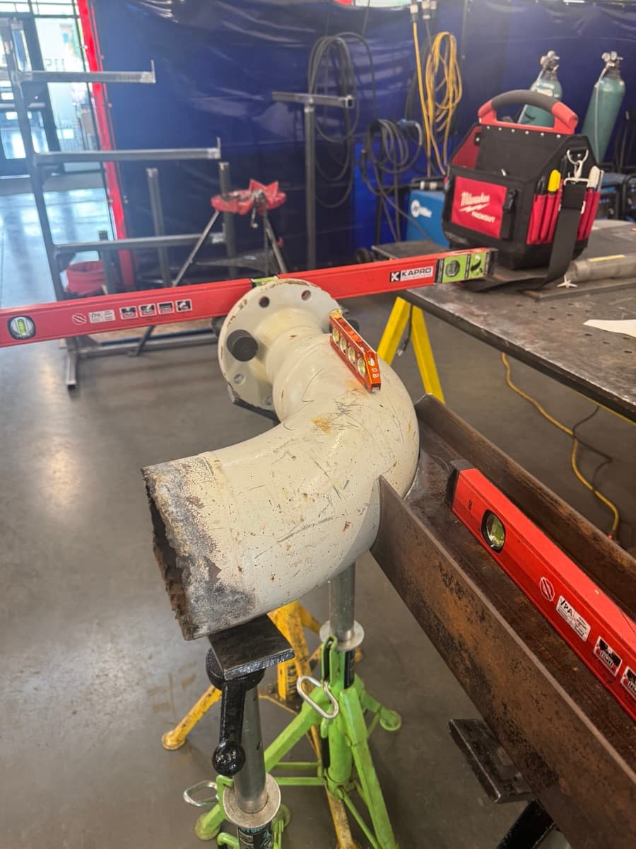 Flanged pipe elbow set up on pipe stands and checked with levels in a welding shop