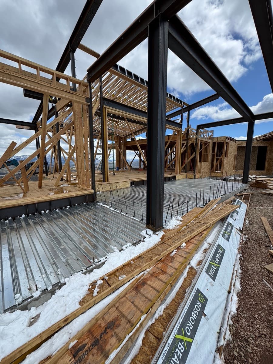 Steel columns and beams over B-deck and rebar, with wood framing going up around it