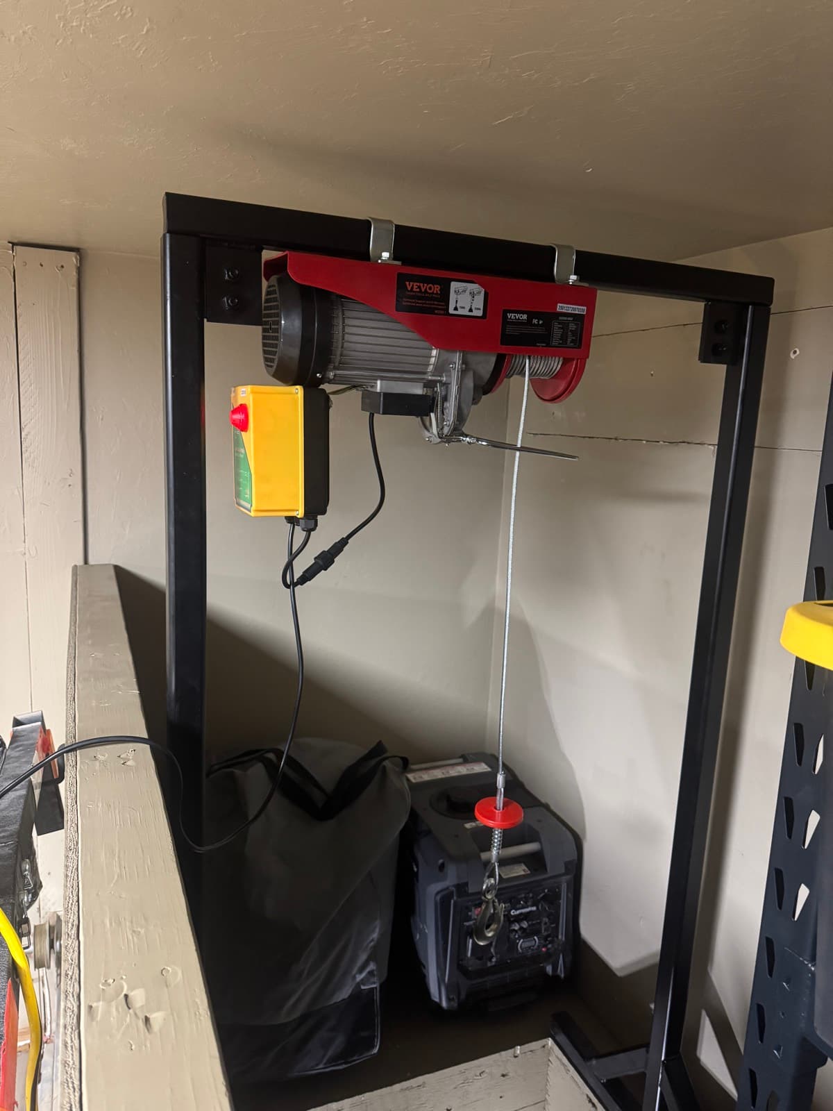 Custom black steel frame holding an electric hoist above a generator on a storage shelf
