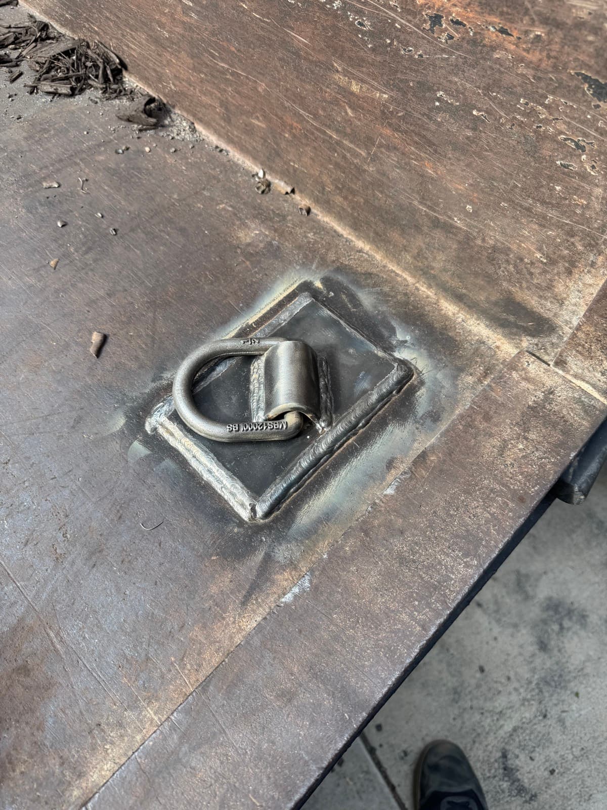 Rated D-ring tie-down welded into the steel bed of a dump trailer
